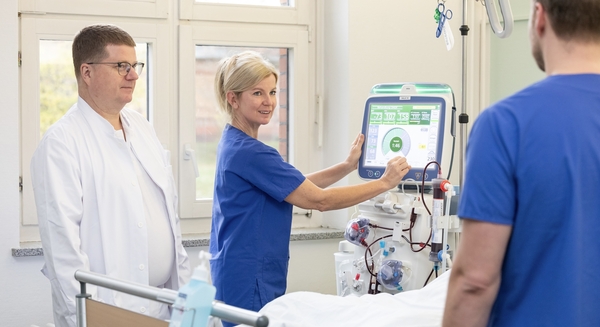 Pflegekraft und Ärzte am Bett eines Dialysepatienten