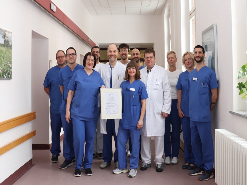 Ärzte und Pflegefachpersonen der Abteilung mit dem gerahmten Zertifikat.
