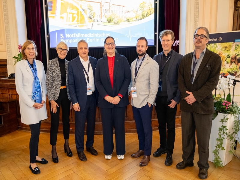 Dr. Andrea Bronner (Ärztliche Direktorin, KEH), Dr. Rotraut Asche (Chefärztin i. R. der Notaufnahme, KEH), Michael Mielke (Geschäftsführer, KEH), Ellen Haußdörfer (Staatssekretärin), Alexander Matthes (Direktor, Sana Klinikum Lichtenberg), Christian Dreißigacker (Geschäftsführer, BG Klinikum Unfallkrankenhaus Berlin) und Dr. Gerold Kretschmar (Chefarzt Notaufnahme, KEH) stehen nebeneinander vor der Bühne
